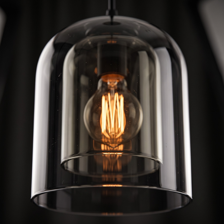Smoked glass pendant light hanging above wooden nightstand in modern bedroom