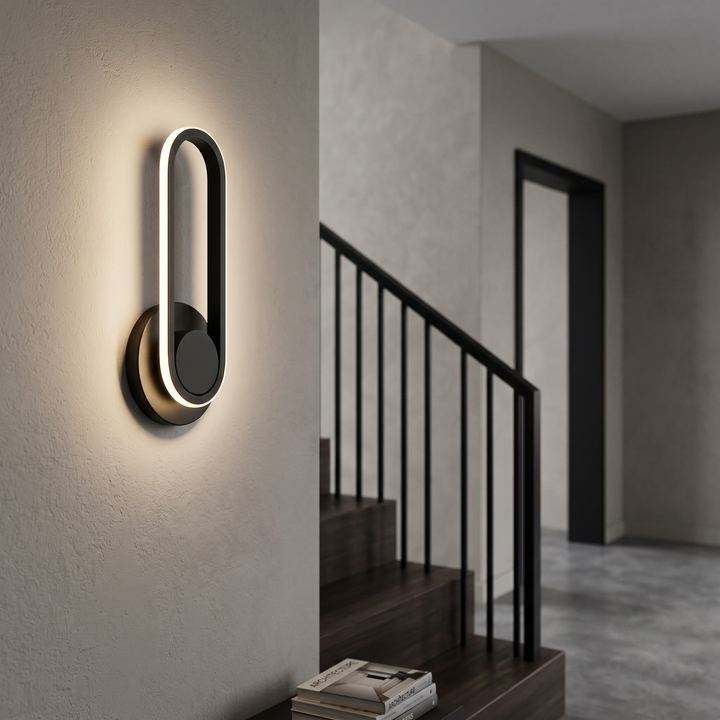 Black rotatable LED wall sconce in modern hallway with warm light